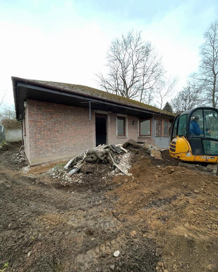 The Baberton golf shop before conversion: a low brick building with a digger and spoil heap on site.