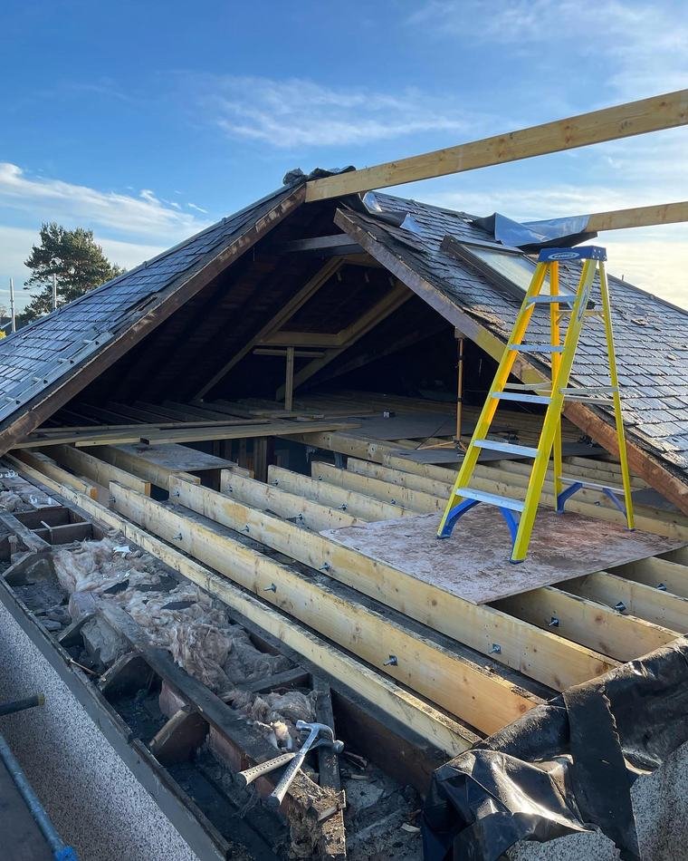 The bungalow with its roof stripped back to the timbers and a ladder standing on new boarding.