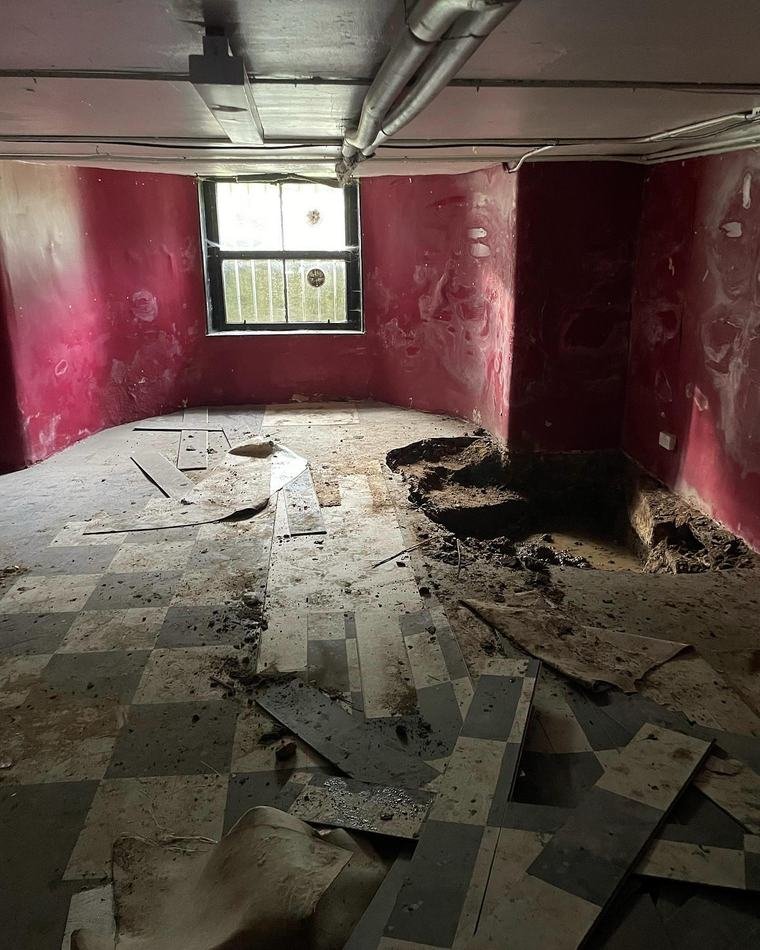 The basement before work: bare painted walls, broken floor tiles and soil dug out of the floor.